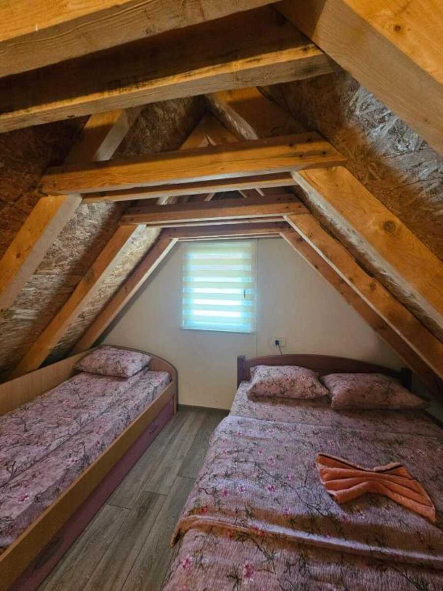Attic room with exposed wooden beams and two beds